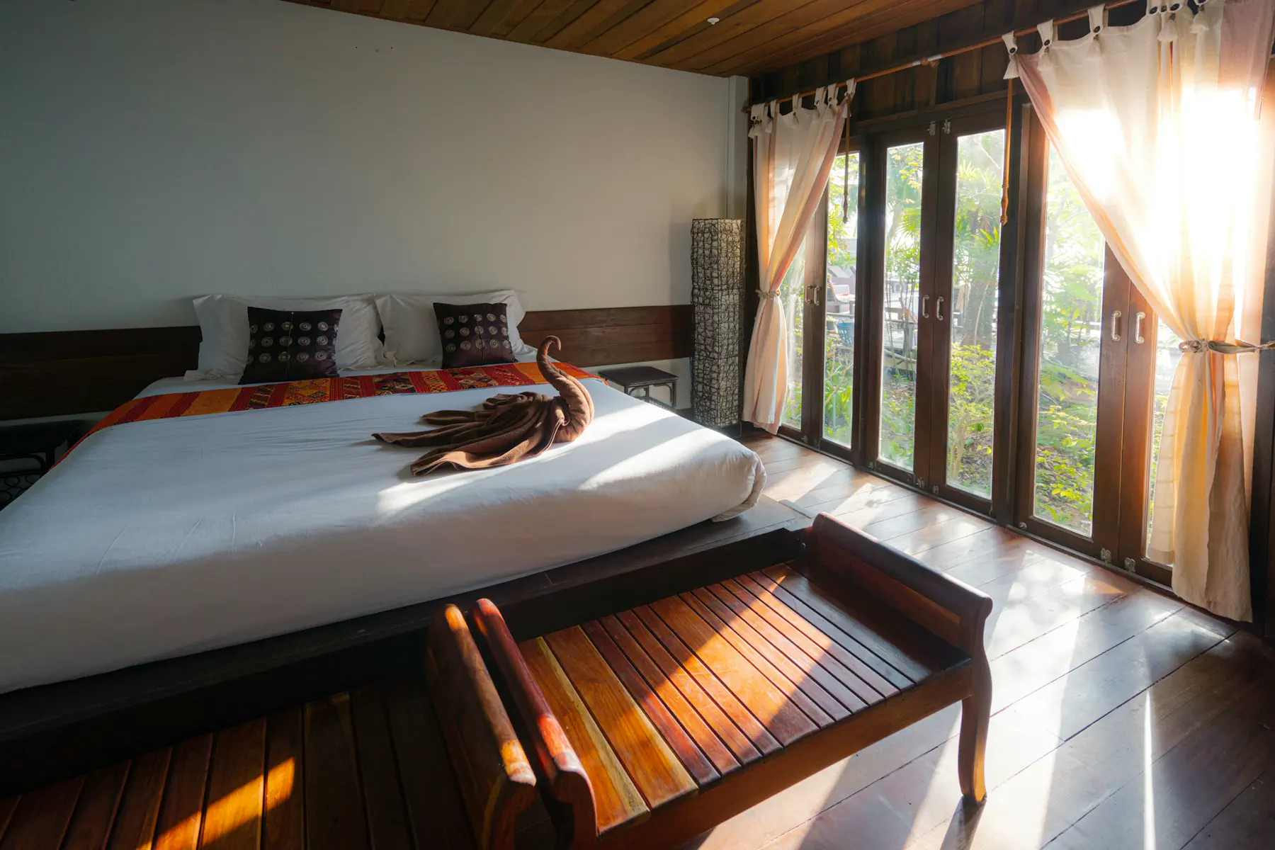 Sunlit hotel suite with taut white linen and a folded towel presentation — editorial still