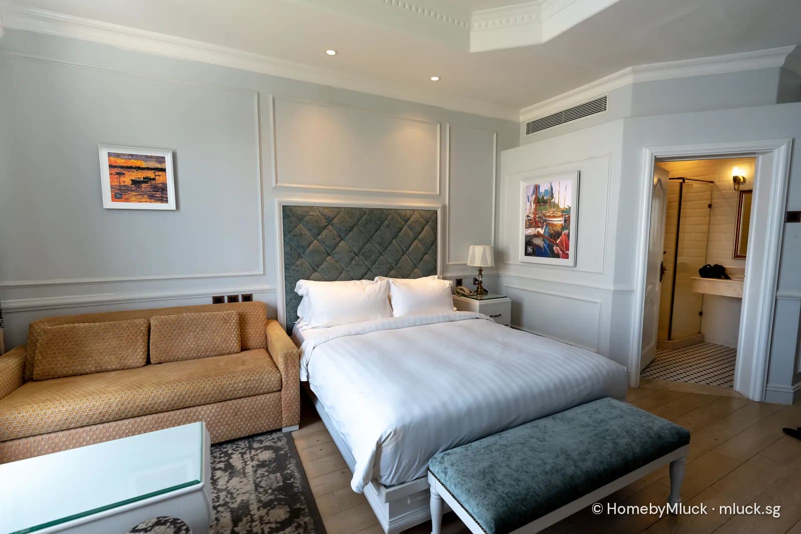 Bright hotel guest room with made bed, sofa and en-suite — licensed Pexels photo