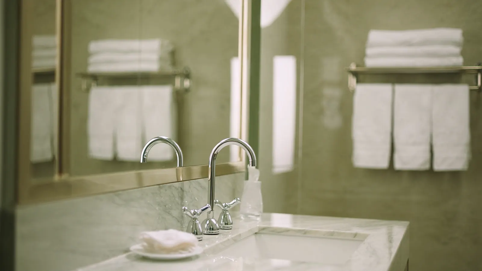 Hotel-style folded towels and polished chrome in a freshly cleaned bathroom